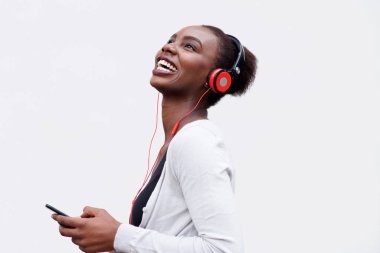 Profile portrait of happy young african american woman listening to music with smart phone and headphones clipart