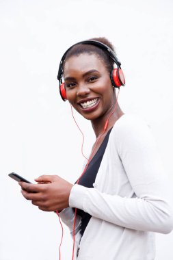 Yan portre güzel genç Afro-Amerikan kadının cep telefonu ve kulaklık ile müzik dinlemek