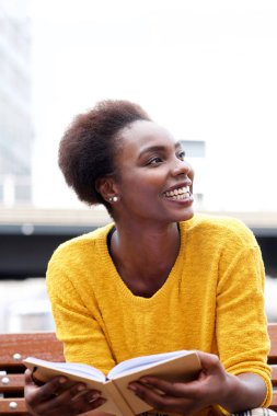 Kitapla dışarıda mutlu Afrikalı-Amerikalı kadın portresi