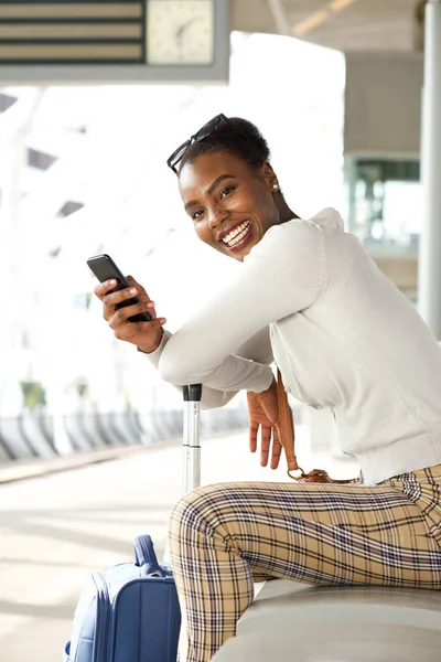 バッグや携帯電話で駅に座って幸せなアフリカ系アメリカ人女性の肖像画 — ストック写真