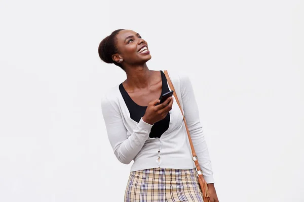 Portrait of young black woman smiling with cellphone against isolated white background