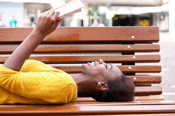 Retrato Jovem Africana Sorridente Deitada Livro Leitura Banco — Fotografia de Stock