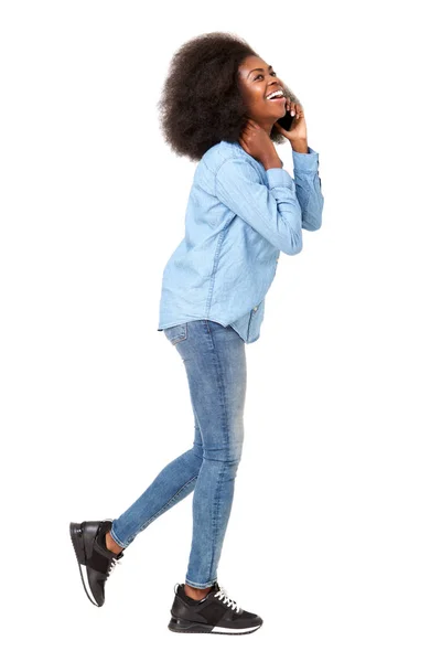 ウォーキングと携帯電話で話す若い黒人の女性の完全なボディ側肖像画 — ストック写真