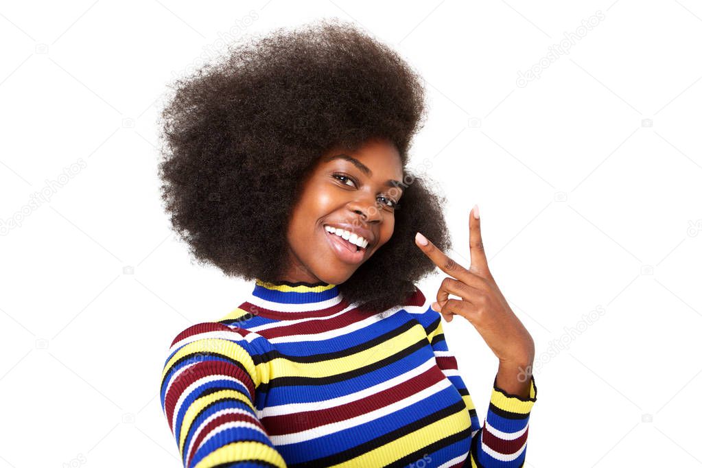 Close up portrait of happy young african american woman taking selfie with peace hand sign against isolated white background