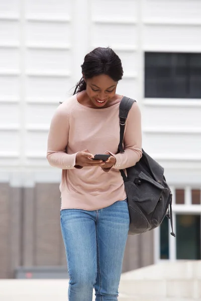 幸せな若い黒人女性歩行と携帯電話を見ての肖像画 — ストック写真