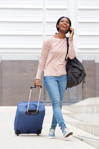 スーツケース バッグと携帯電話と一緒に歩いている幸せな若いアフリカ系アメリカ人女性の全身肖像画 — ストック写真