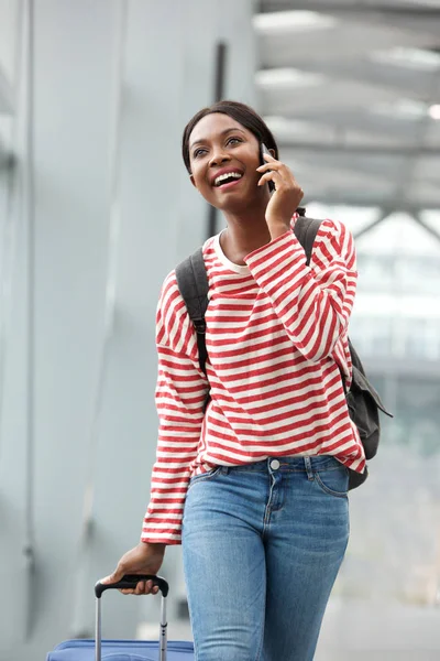 ウォーキングとターミナル空港で携帯電話で話す幸せの若いアフリカ系アメリカ人女性の肖像画 — ストック写真