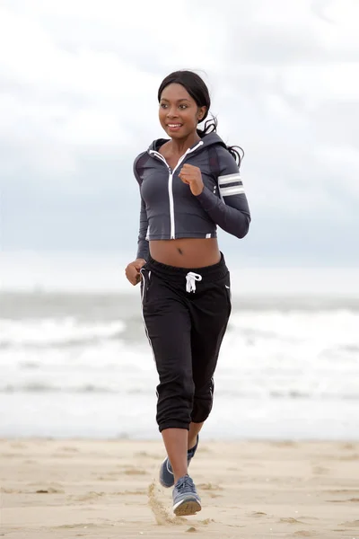 ビーチで走っている若い黒スポーツ女性の全身肖像画 — ストック写真
