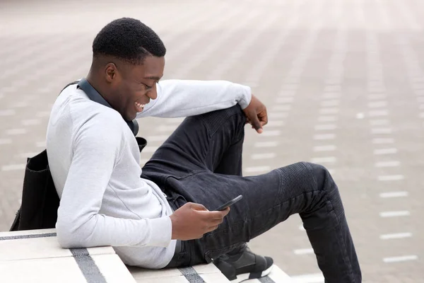 Retrato Lateral Del Joven Negro Sonriente Sentado Afuera Con Teléfono — Foto de Stock