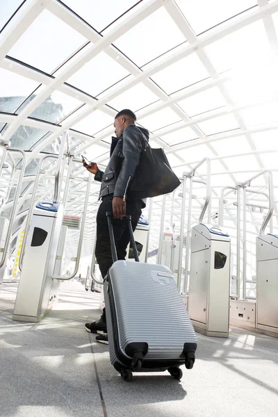 スーツケースと駅で携帯電話と一緒に旅行する若い男の全身肖像画 — ストック写真