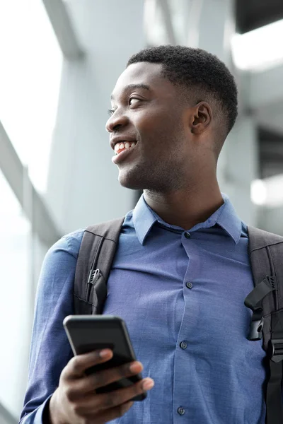 El çantası ve akıllı telefon ile mutlu Afrika kökenli Amerikalı adam portresi kadar kapatın