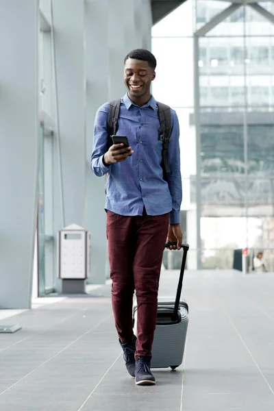 バッグと駅で携帯電話と一緒に旅行する若い男の全身肖像画 — ストック写真