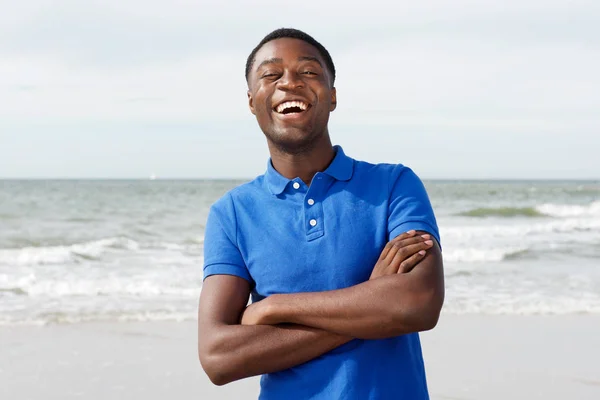 愉快的年轻黑人的画像笑了胳膊横渡在海滩 — 图库照片
