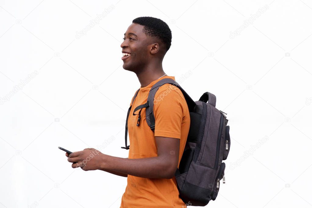 Side portrait of happy young african american man walking against isolated white background with mobile phone 