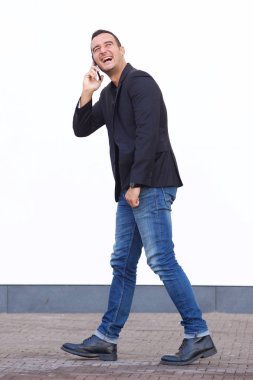 Tam vücut yan yürüyüş ve cep telefonu ile konuşurken mutlu bir adam portresi