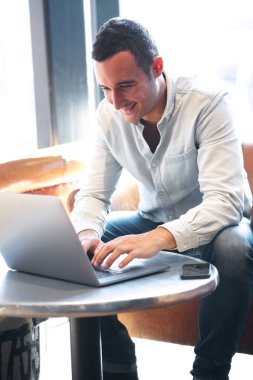 Laptop ile kafede oturan gülümseyen adam portresi 