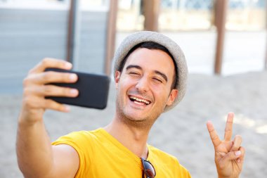 Selfie akıllı telefon ile plajda alarak şapka ile mutlu bir adam portresi kadar yakın