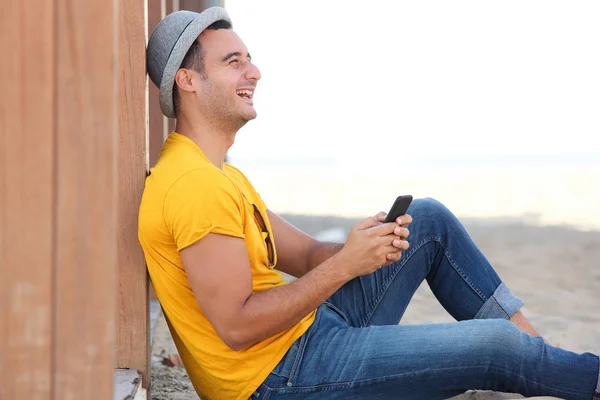 Sida Porträtt Lycklig Man Sitter Sand Stranden Med Mobiltelefon — Stockfoto