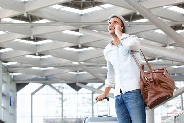 Portrait of happy travel man walking and talking on mobile phone at station