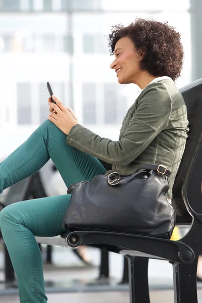 Боковой Портрет Африканской Американки Сидящей Скамейке Смотрящей Мобильный Телефон — стоковое фото