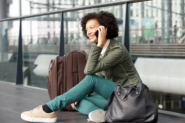 荷物と携帯電話で話していると駅で床に座ってアフリカ系アメリカ人の女性の肖像画 — ストック写真