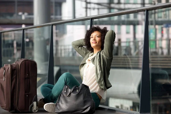非洲裔美国旅游妇女的肖像坐在车站地板上与手提箱 — 图库照片