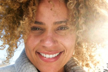 Kameraya bakarak kıvırcık saçlı güzel genç Afro-Amerikan kadın portresi yüz kadar kapatın