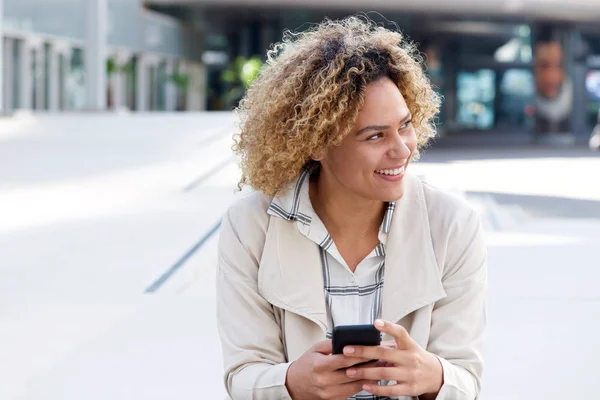 外の携帯電話で笑顔の若いアフリカ系アメリカ人女性の肖像画 — ストック写真