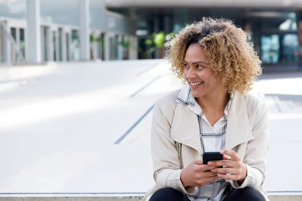 スマート フォンで外の笑顔の若いアフリカ系アメリカ人女性の肖像画 — ストック写真