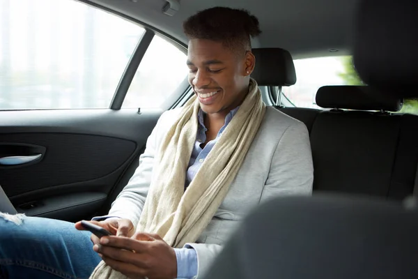 Portrét Usměvavý Mladík Afroamerické Při Pohledu Mobilní Telefon Sedadle Auta — Stock fotografie