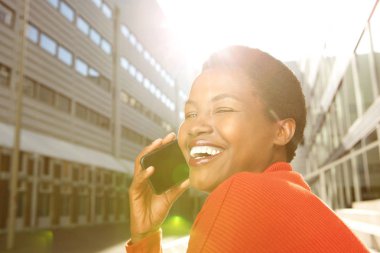 Telefonda konuşan ve gülen genç siyah kadın portresi yan kapatmak