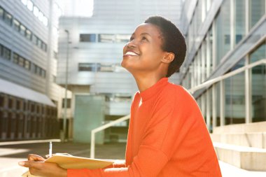 Kitap ve kalem ile gülümseyerek mutlu bir genç kadın portresi yan 