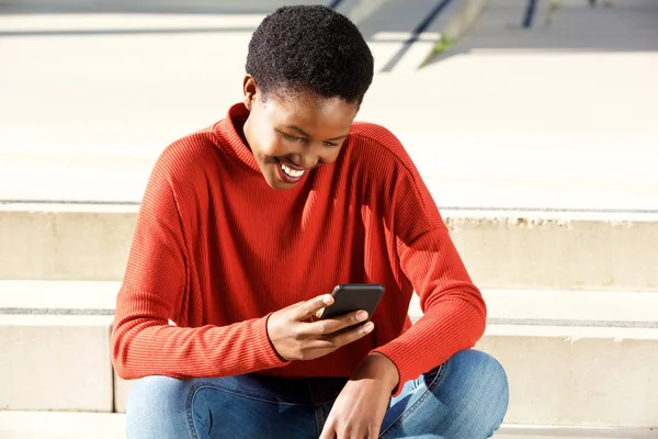 Portret Van Lachende Jonge Zwarte Vrouw Kijken Naar Mobiel Buiten — Stockfoto