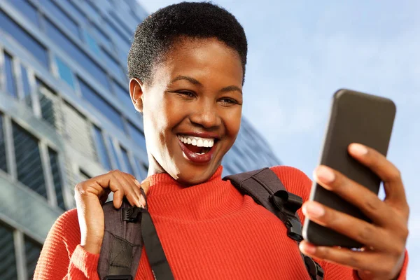 Close up portrait of happy young african woman holding cellphone in city