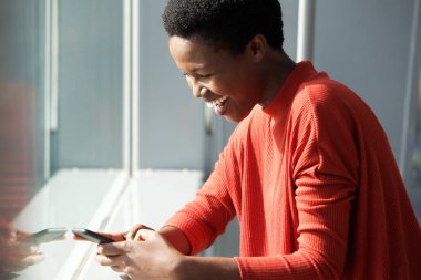 Mutlu genç Afro-Amerikan kadın cellphone tarafından pencere bakarak yan portresi