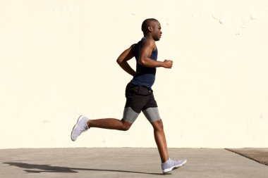 Tam vücut profil duvarı ile çalışan genç Afro-Amerikan adam portresi