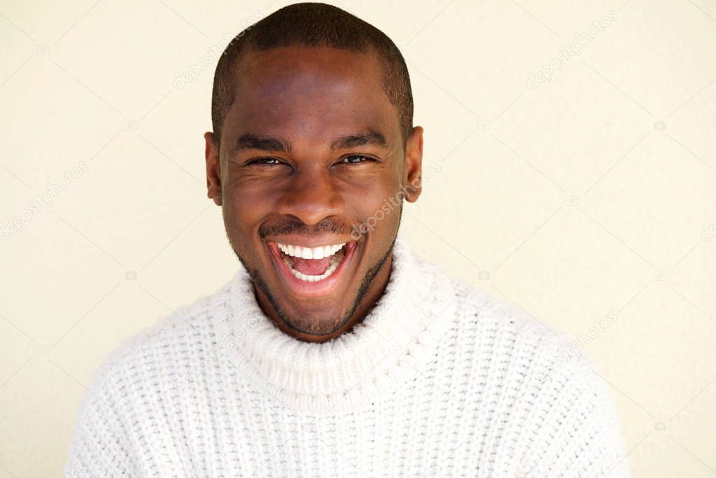 Close up portrait of cheerful african american man laughing against light background