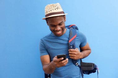 Çanta ve cep telefonu mavi arka plan serin genç Afro-Amerikan adam portresi