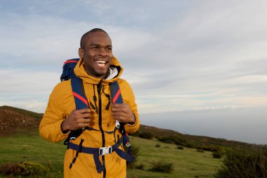 Doğada yürüyüş sırt çantası ile genç siyah erkek gülümseyen portresi