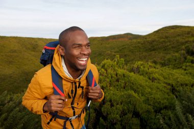 Mutlu Afro-Amerikan erkek backpacker doğada yürüyüş portresi 