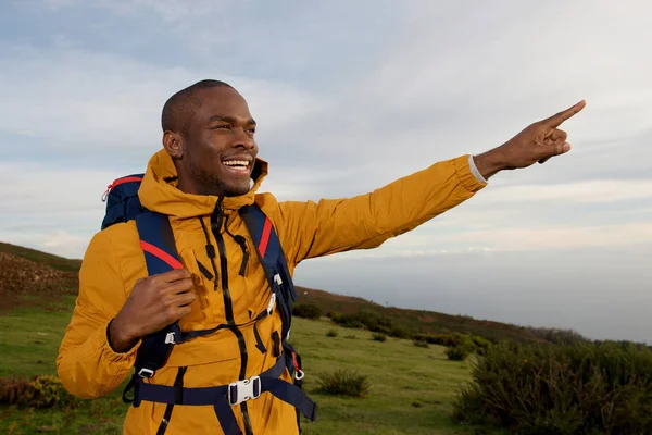 指屋外で自然を指している幸せのアフリカ系アメリカ人のハイカーの肖像画 — ストック写真