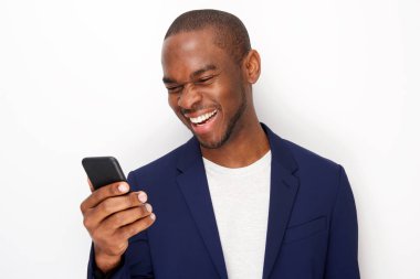 Beyaz duvar ile cep telefona bakarak gülümseyen genç siyah adam portre yakın 