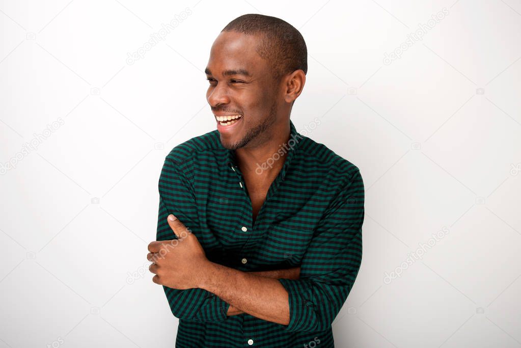 Portrait of attractive young black man smiling against white background with arms crossed