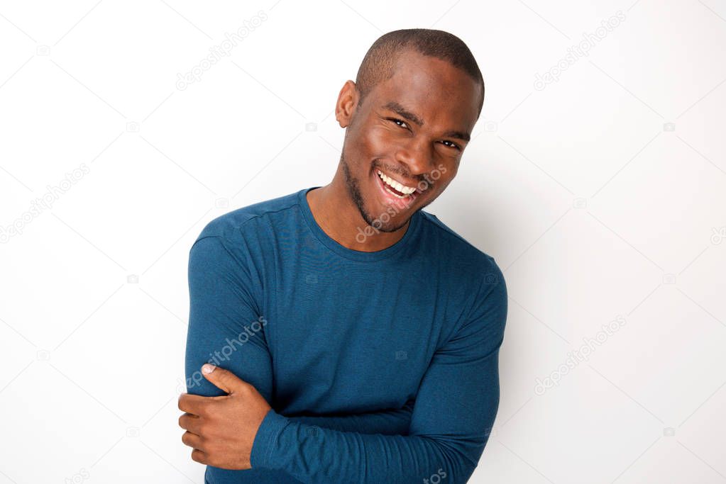 Portrait of handsome young black man smiling with arms folded by white background