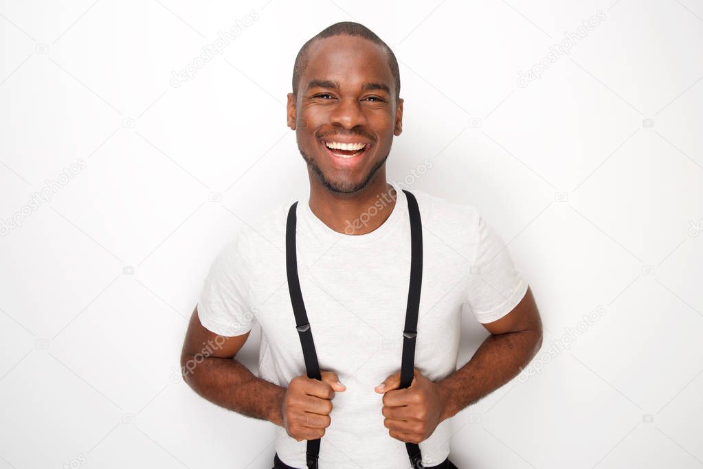 Portrait of happy black man posing with suspenders against white background