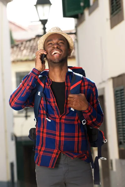 バックパックと笑顔と携帯電話で話しているアフリカ系アメリカ人旅行男の肖像 — ストック写真