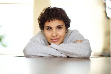 Kameraya bakarak kollarına yaslanmış güzel genç afro-amerikan kadının yakın portresi