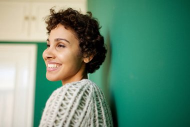 Yeşil duvara karşı gülümseyen Afrikalı Amerikalı kadının yakın yan portresi