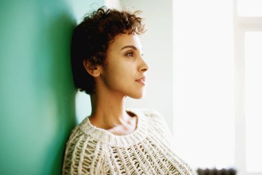 Duvara yaslanmış ve düşünen güzel Afro-Amerikan kadının yan portresi