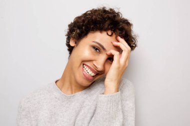 Beyaz duvarla elle gülen mutlu genç Afro-Amerikan kadının yakın portresi